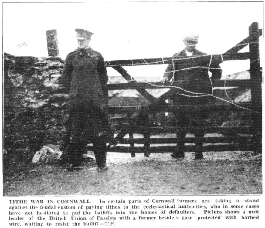 Tithe War in Cornwall. In certain parts of Cornwall farmers are taking a stand against the feudal custom of paying tithes to the ecclesiastical authorities, who in some cases have not hesitated to put the bailiffs into the homes of defaulters. Picture shows a unit leader of the British Union of Fascists with a farmer beside a gate protected with barbed wire, waiting to resist the bailiff.